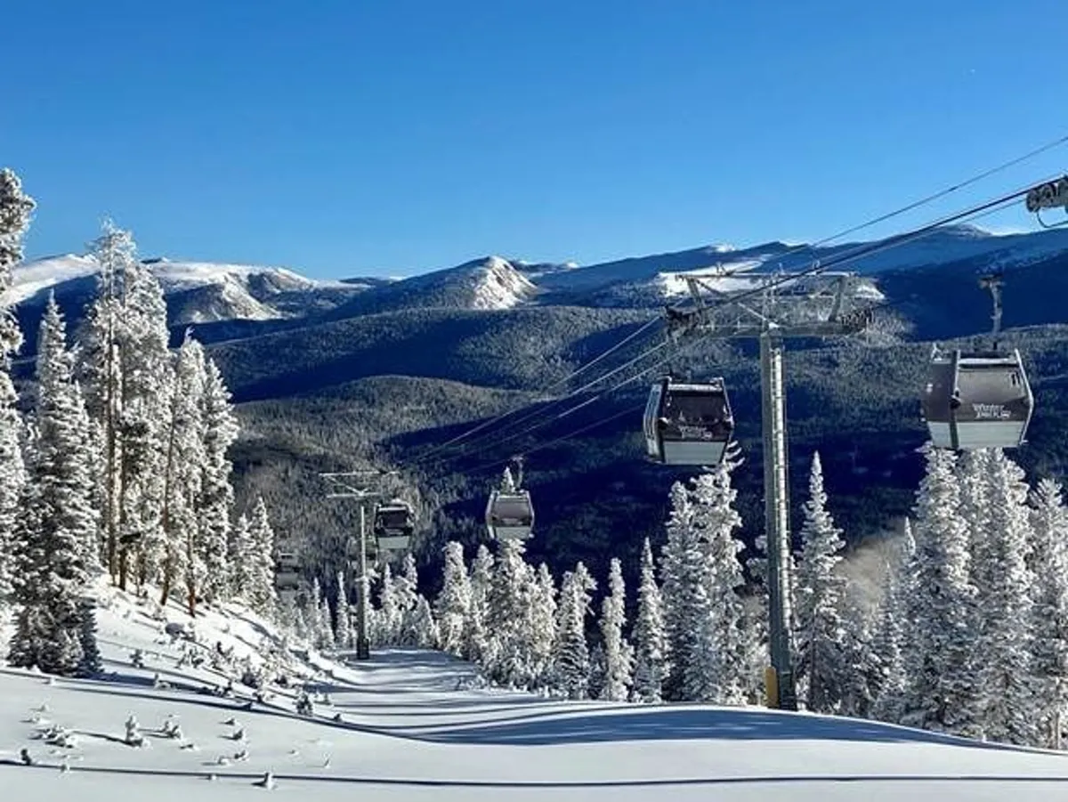 This image showcases a lively winter scene with a ski lift gliding above snow-covered trees and a breathtaking mountain range in the background. Adventurers are seen skiing, snowboarding, and snowshoeing, all set against a colorful sky as the sun sets. The mood is both peaceful and full of possibility, capturing the spirit of winter exploration in Winter Park.